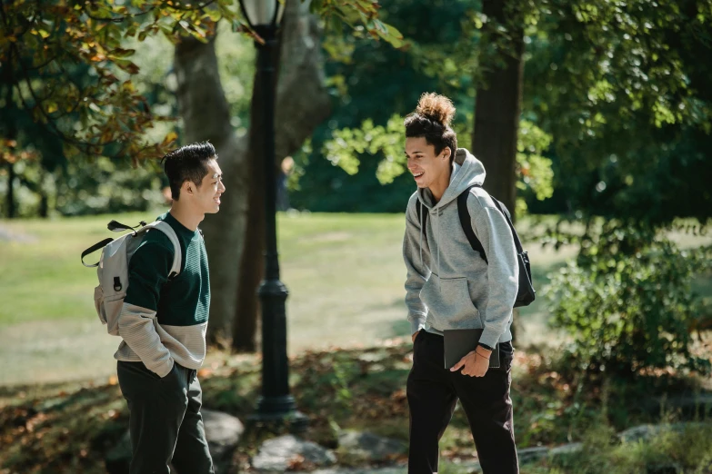 two young people who are talking while holding onto their skateboards