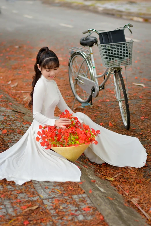 a girl in white holding a bouquet of red flowers near her bike