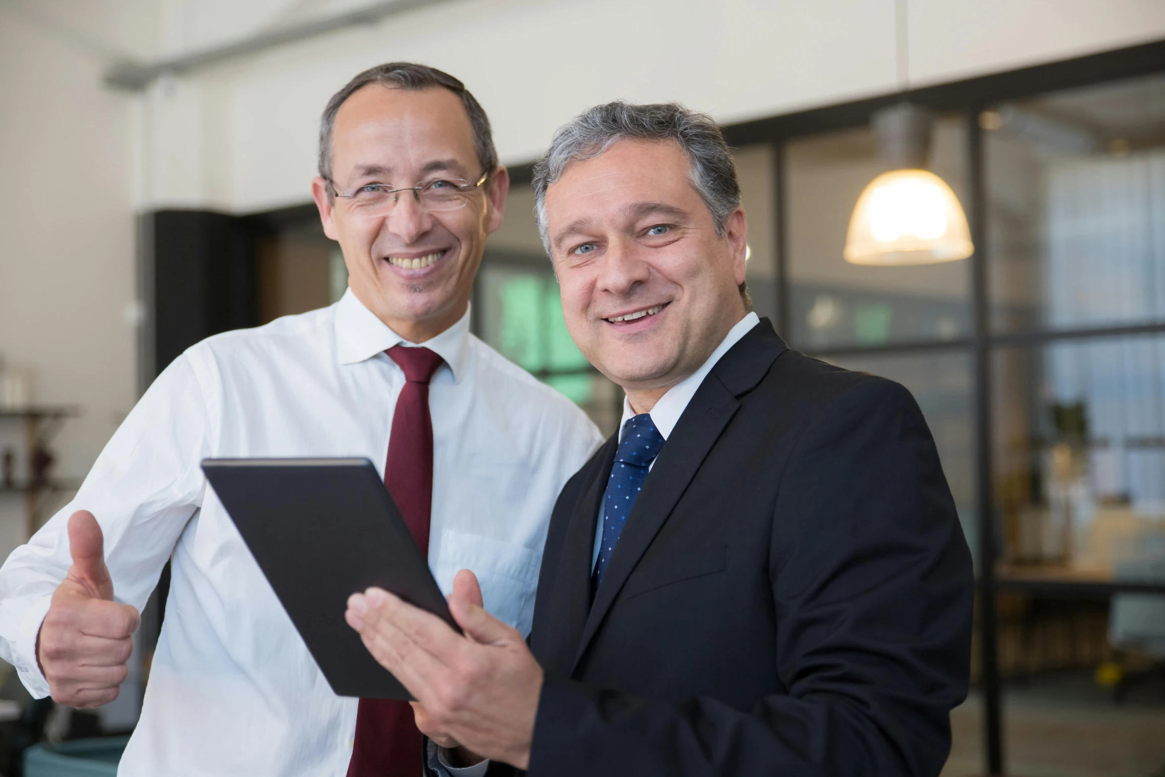 two men standing next to each other near a laptop