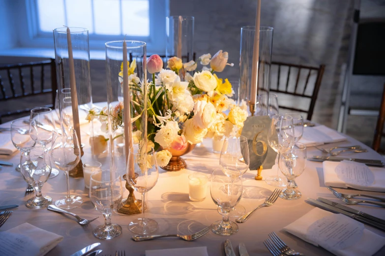 a decorated table with tall candles and white floral centerpieces