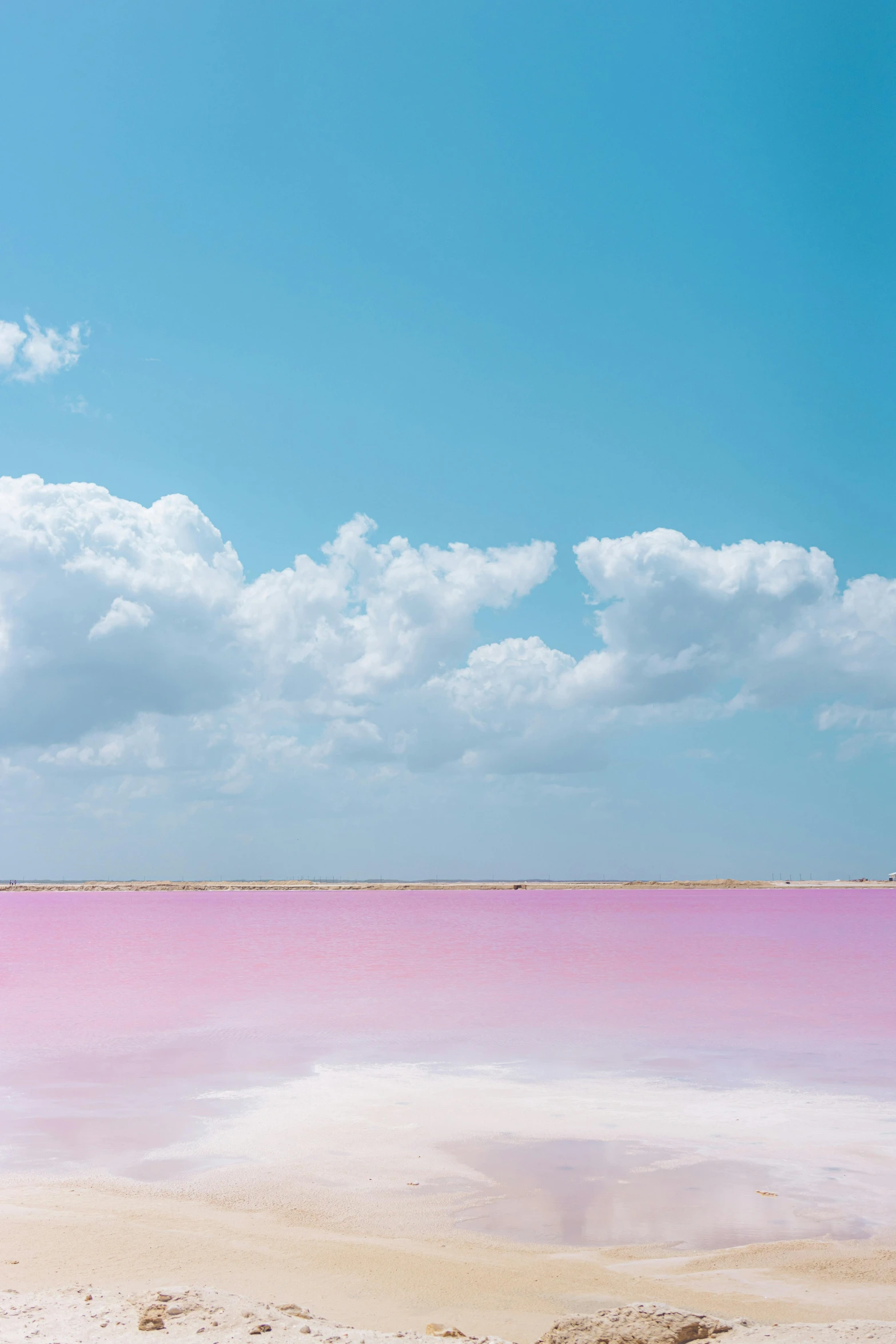 a large pink body of water with a few clouds