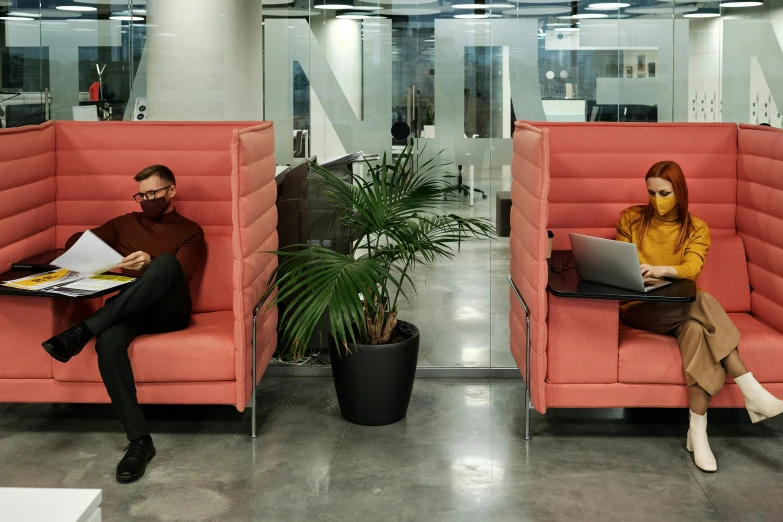 a man and woman sitting in orange chairs on their computers