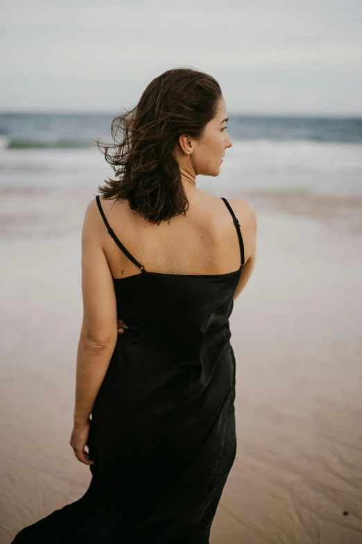 woman with dark hair standing on the beach