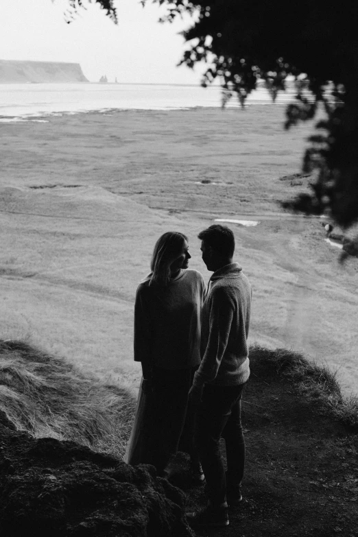 two people standing near the water looking out at the ocean