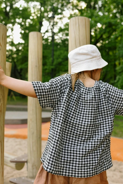 a woman holding onto a wooden fence in a park