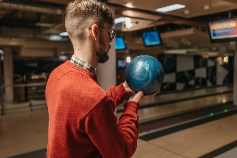 a man in a red shirt holding a blue bowling ball