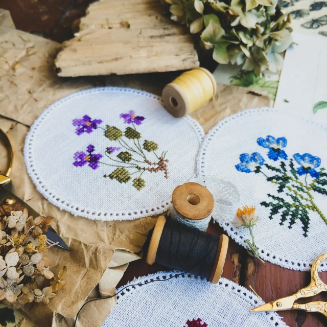 needle and thread and flower designs laid out on leaves