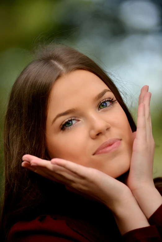 a woman posing for the camera while holding her hand on her face