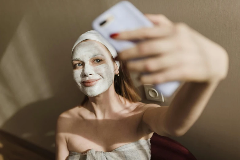 a girl wearing white face paint on her face is taking a selfie