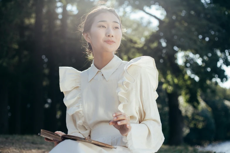 a woman wearing a white dress and holding a wood block in her hand