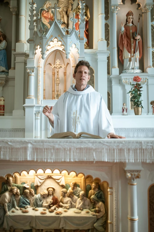 a priest sits in front of a chapel with angels