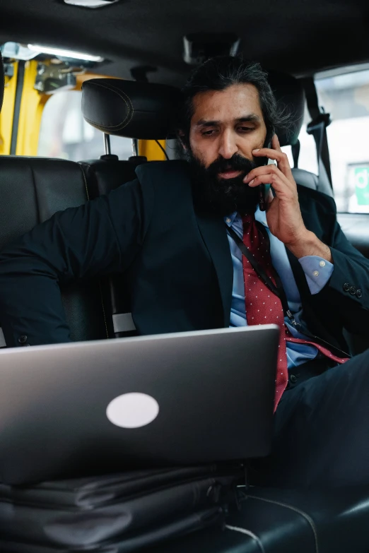 man with beard sitting in the bus and using a laptop