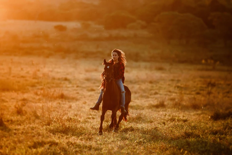 two people riding horses through a grassy field