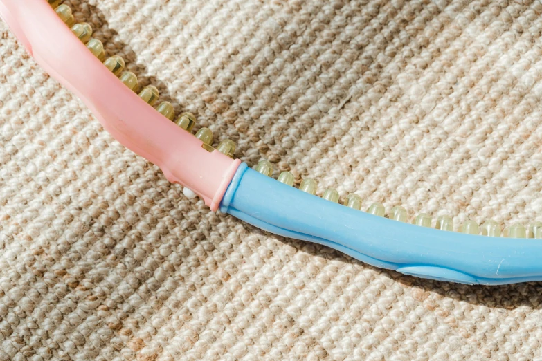 a pink and blue toothbrush laying on top of a tan rug