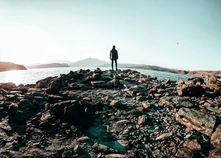 a man standing on the rocks by the water