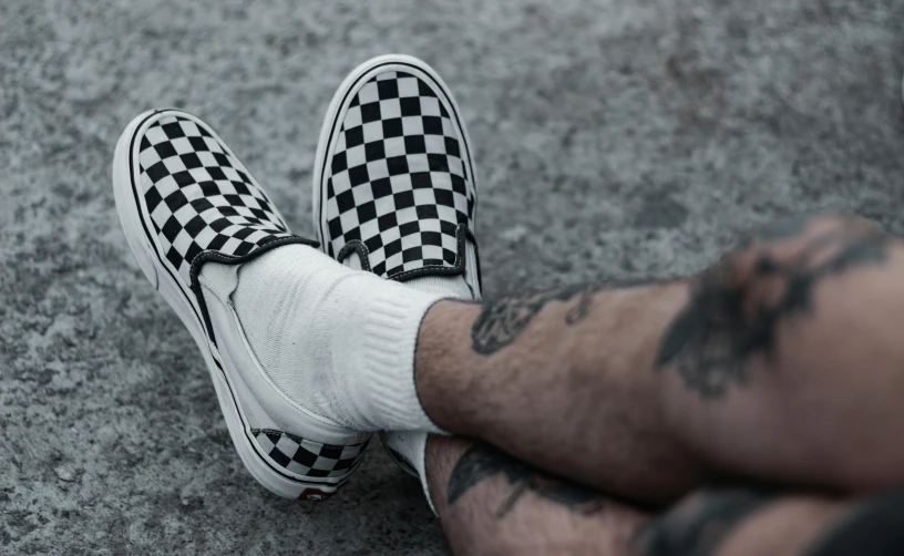 a man's legs with tattoos and some checkered shoes