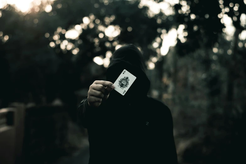 the silhouette of a hooded figure with a white card