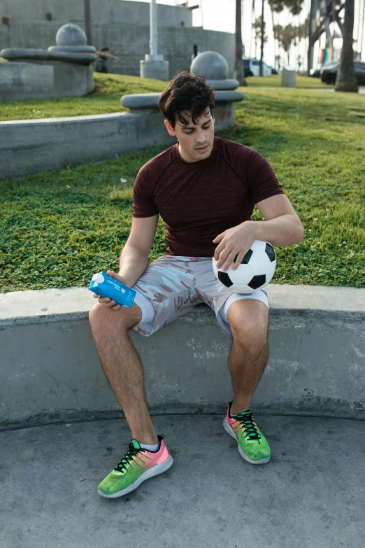 a young man is sitting outside on the curb