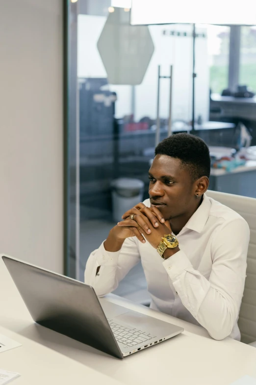 the young man is sitting at the table with his laptop in front of him