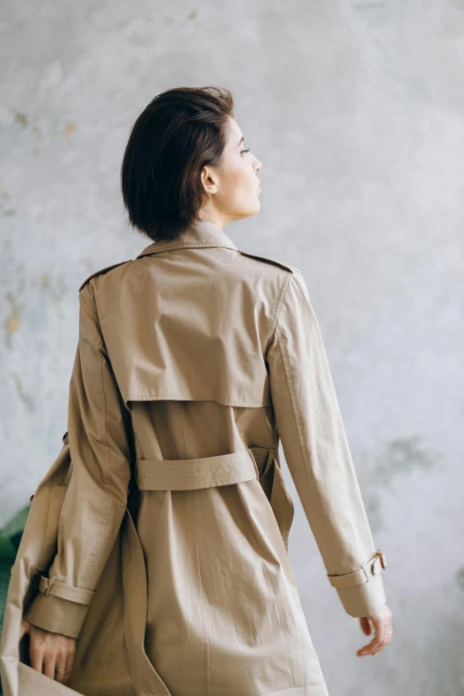 a woman in a tan trench coat and tan slacks