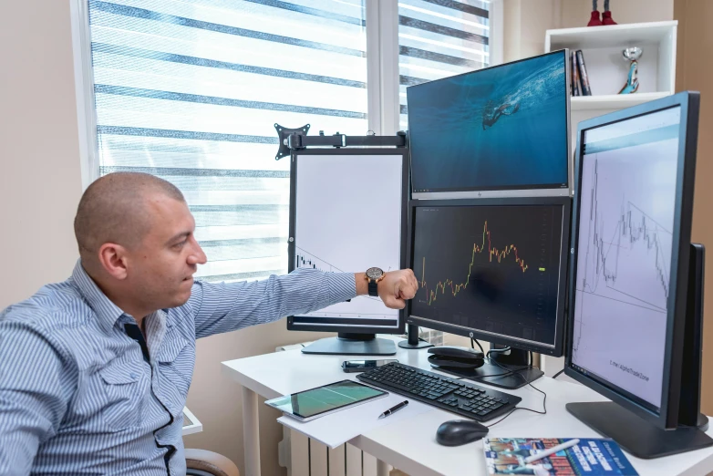 a man is pointing at two monitors on a desk