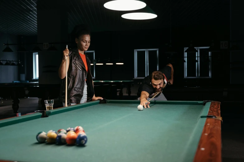 two men play a game of pool in a dark room