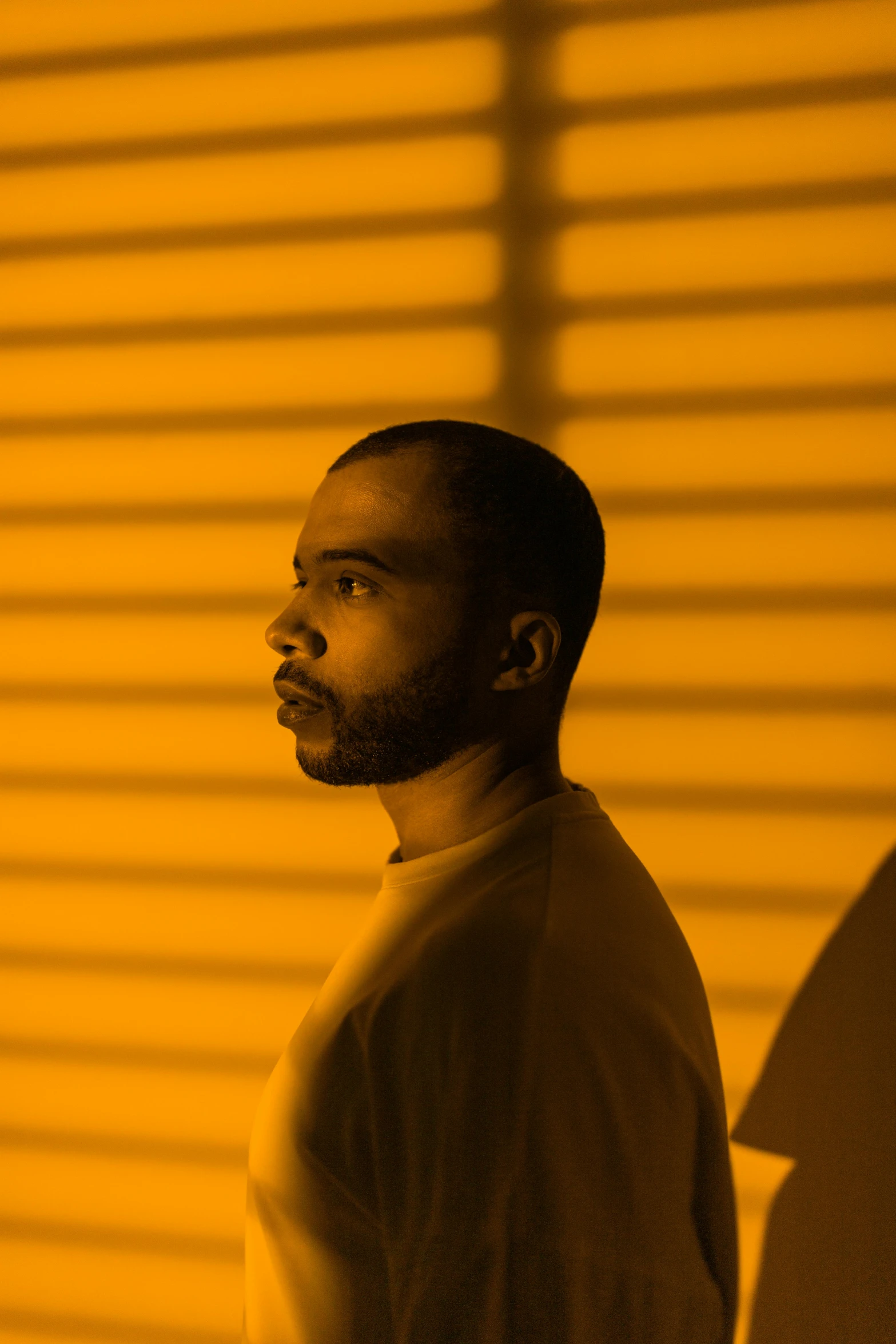 a black man staring away in a yellow room