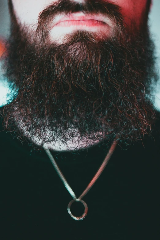 a man with a beard and ring pendant on his neck