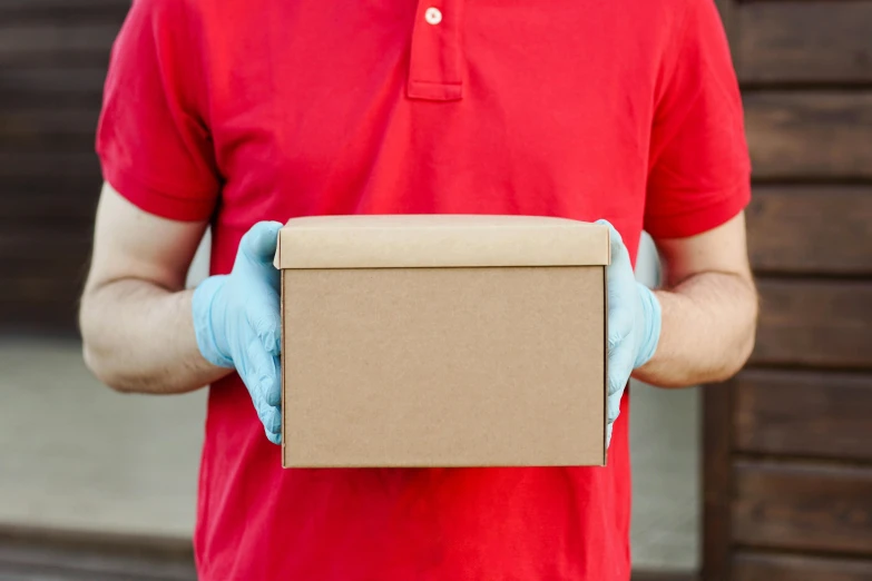 man wearing blue gloves is holding a brown box