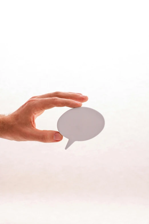 a persons hand holding a paper speech bubble