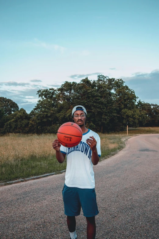 a man with a basketball standing by the side of the road