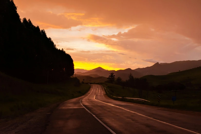 a long road is shown in the background, and the sun sets