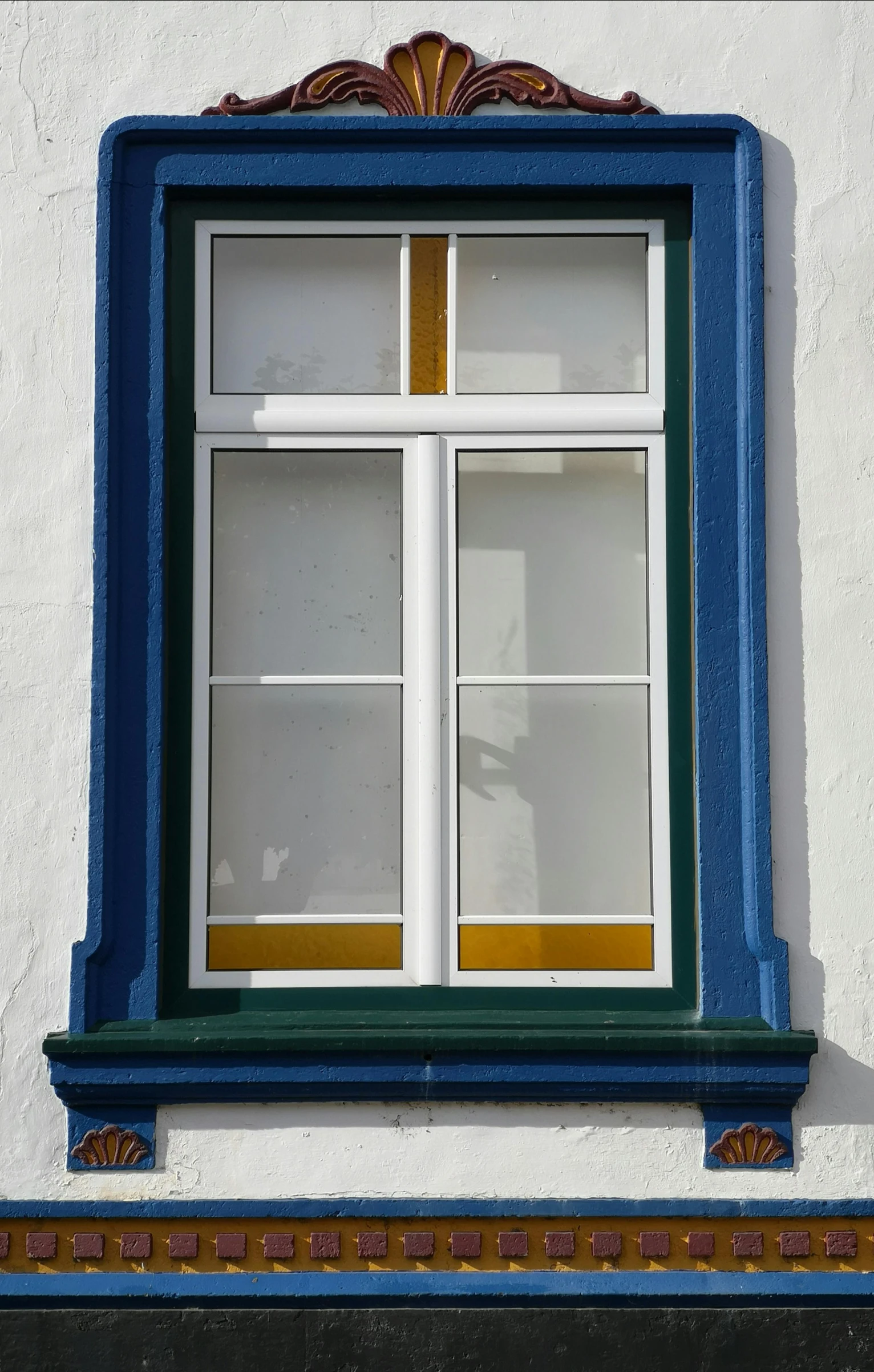 the window is next to the brown and blue trim