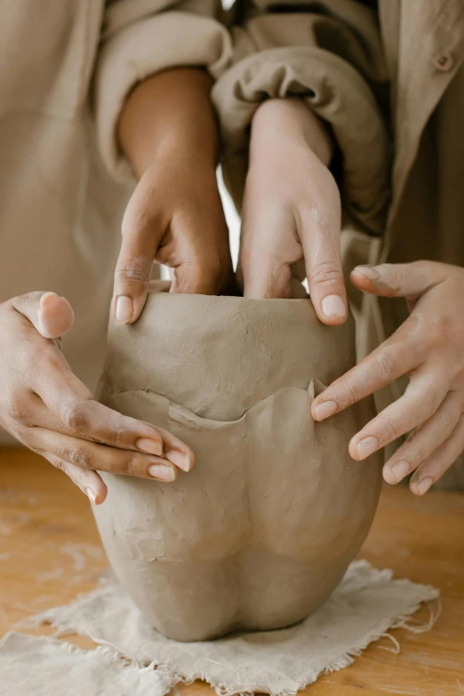 hands are doing a pottery work on a clay pot