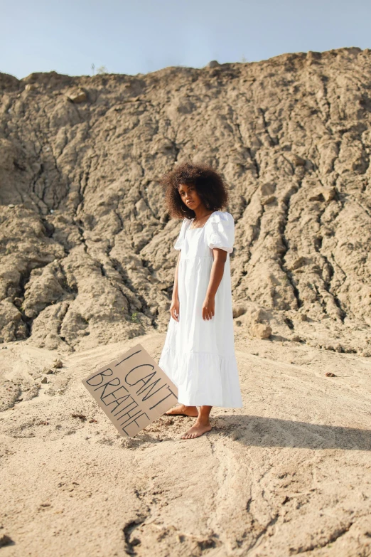 a little girl standing on a hill in the sand