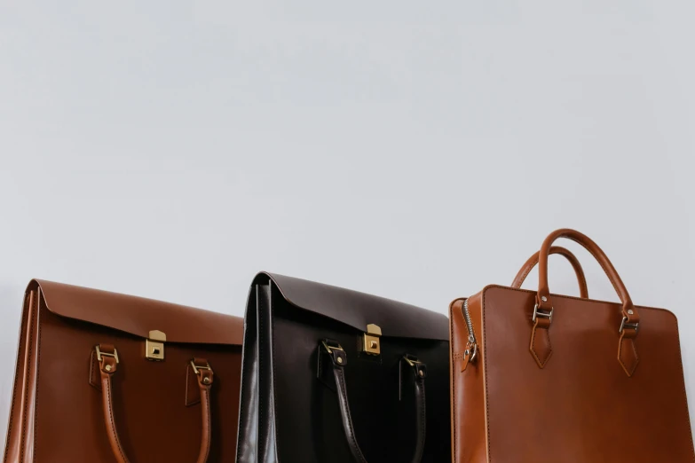 three leather briefcases sitting side by side on a table