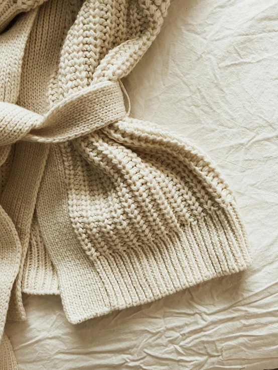 an unmade white blanket laying on top of a bed