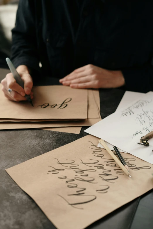 someone writing on brown paper with pen and notebook