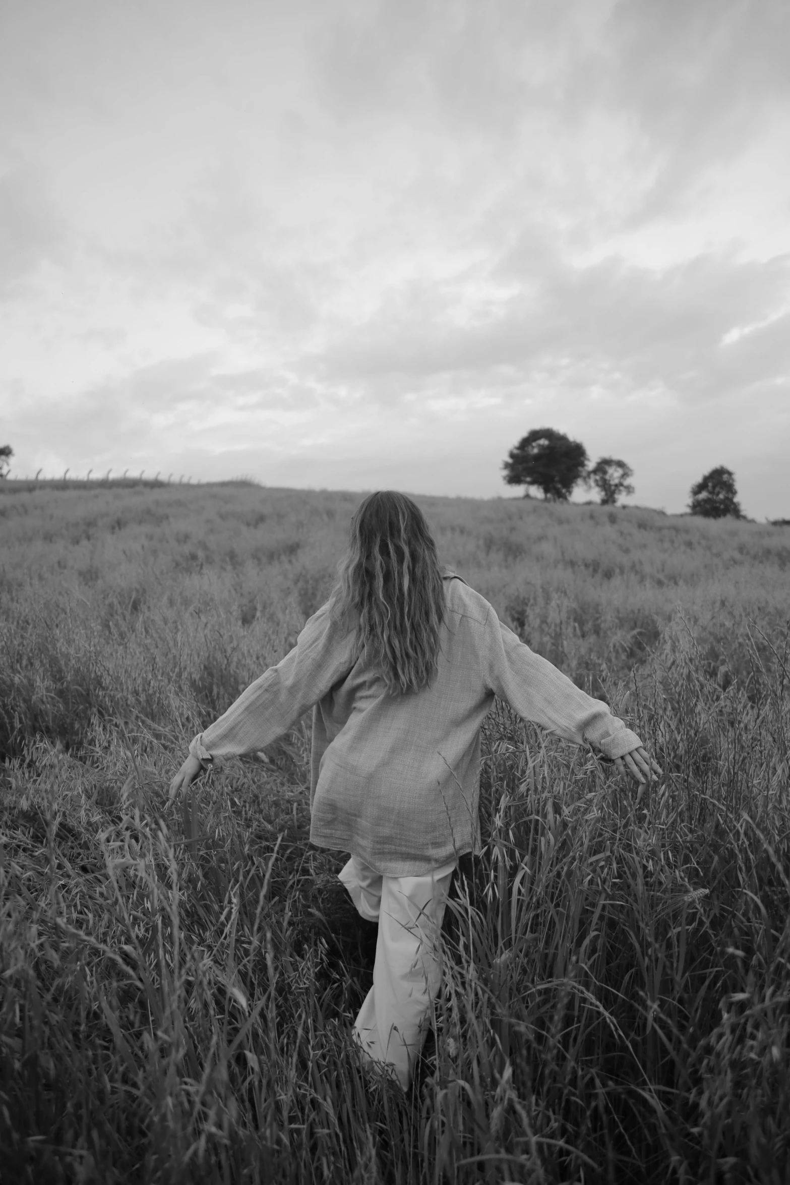 a woman is running in the grass with her hands spread out