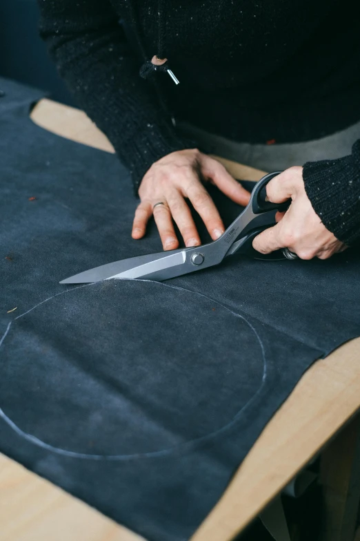 person using scissors to cut fabric on table