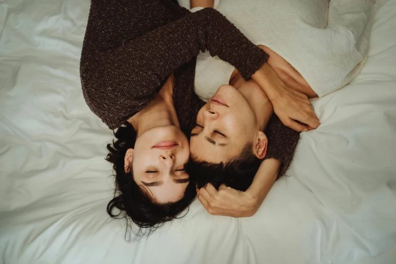 an attractive couple cuddle while lying on a bed