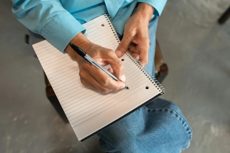 someone holding a pen and notebook while sitting down