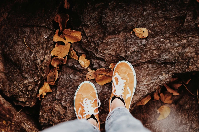 a person is standing on some rocks with a yellow shoe