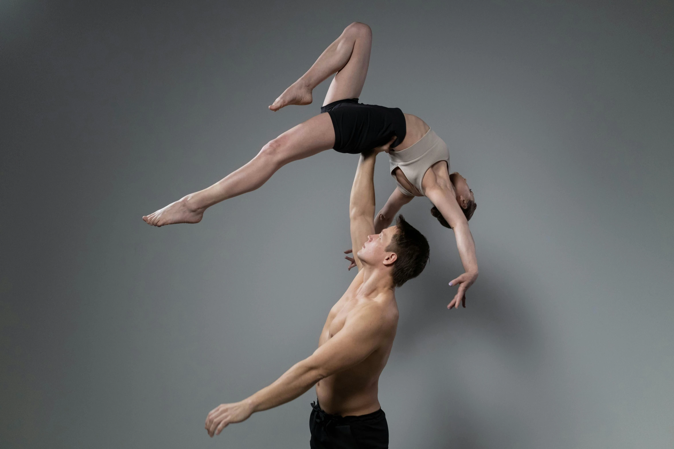 the couple are performing acrobatic ballet moves in the studio