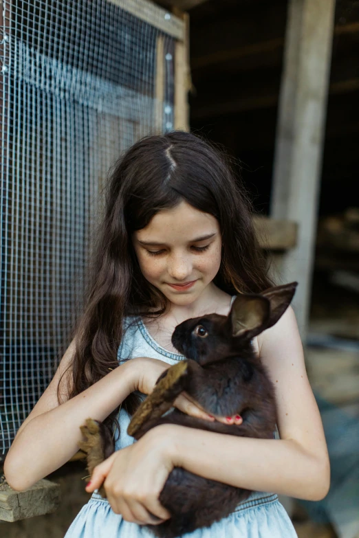 a girl holding a pet bunny while looking at the camera