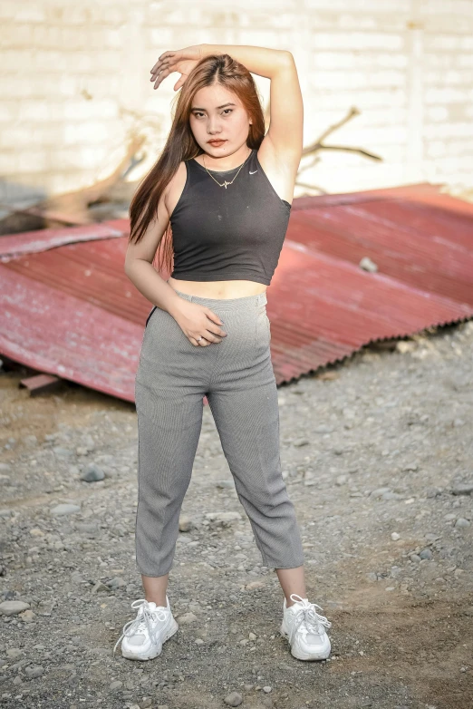 girl in high - waisted pants poses against a wall