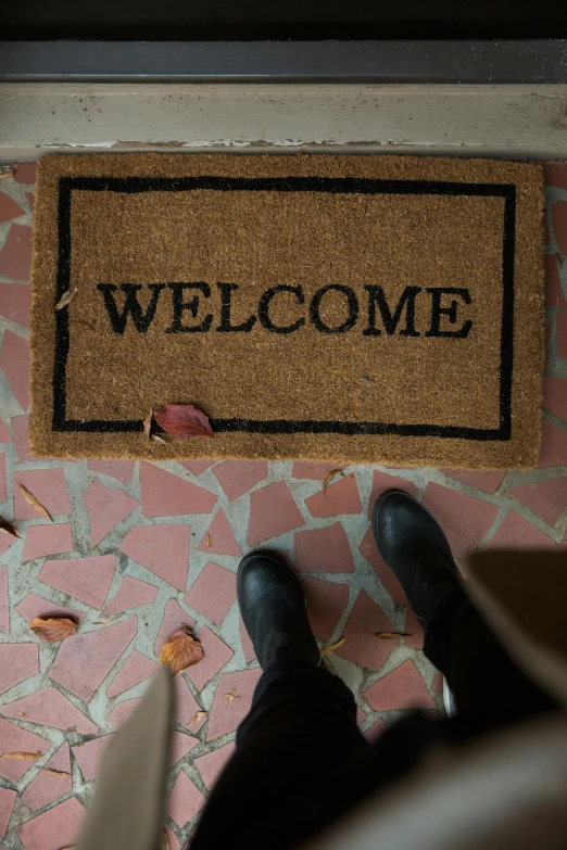 a welcome mat placed beside a persons feet