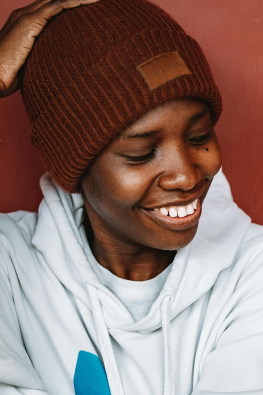 a woman in a white sweater with a brown hat over her head