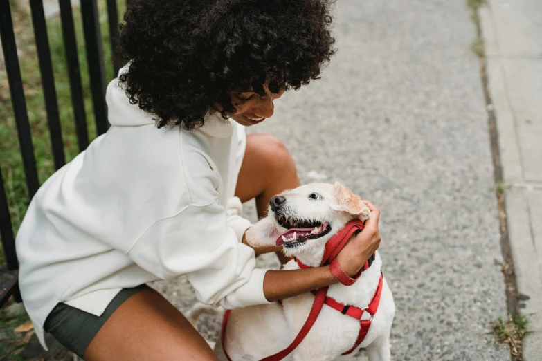 a woman with an afro is petting a small dog