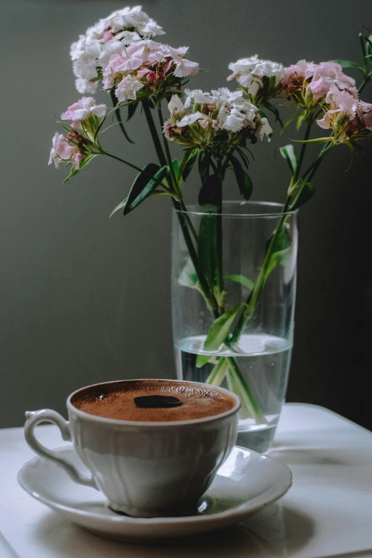 a cup of coffee and a vase with flowers in it